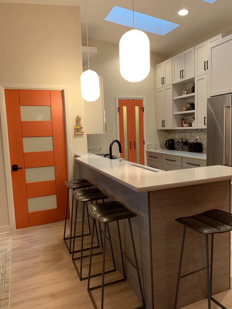 This is an example of a small modern galley eat-in kitchen in Milwaukee with an undermount sink, shaker cabinets, grey cabinets, quartz benchtops, multi-coloured splashback, mosaic tile splashback, stainless steel appliances, laminate floors, a peninsula, beige floor and grey benchtop.