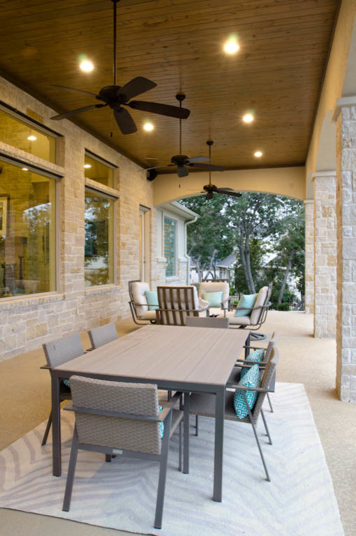 This is an example of an expansive traditional backyard verandah in Austin with concrete slab and a roof extension.