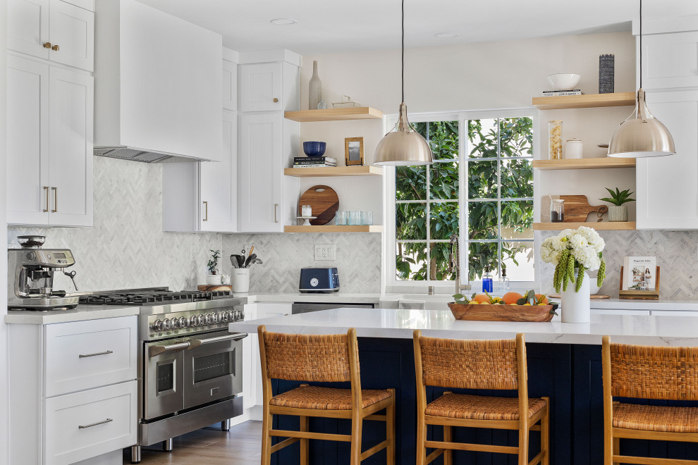 Inspiration for a mid-sized modern l-shaped light wood floor and brown floor eat-in kitchen remodel in Orange County with recessed-panel cabinets, white cabinets, marble countertops, white backsplash, stainless steel appliances, an island, white countertops and a farmhouse sink