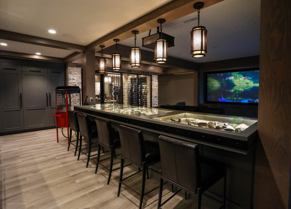 Photo of a large traditional l-shaped seated home bar in Other with an undermount sink, beaded inset cabinets, grey cabinets, glass benchtops, glass sheet splashback and porcelain floors.
