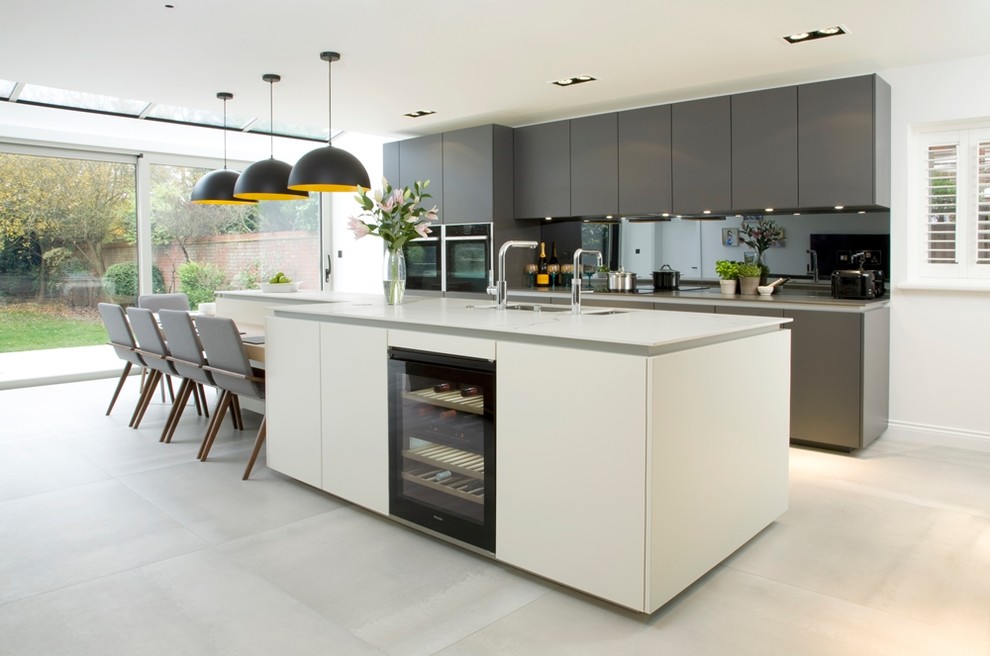 Design ideas for a mid-sized contemporary single-wall eat-in kitchen in London with an undermount sink, flat-panel cabinets, white cabinets, mirror splashback, with island and grey floor.