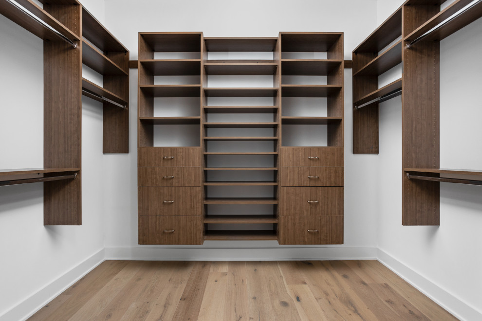 This is an example of a large modern walk-in wardrobe for women in Indianapolis with flat-panel cabinets, medium wood cabinets, light hardwood flooring and multi-coloured floors.