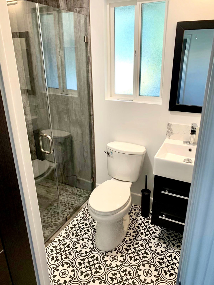Small transitional brown tile and porcelain tile ceramic tile, white floor and single-sink alcove shower photo in Los Angeles with flat-panel cabinets, black cabinets, a one-piece toilet, white walls, an integrated sink, solid surface countertops, a hinged shower door, white countertops and a floating vanity