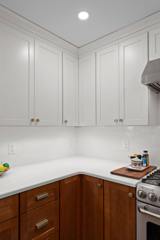 Example of a small u-shaped light wood floor and brown floor eat-in kitchen design in Boston with a drop-in sink, shaker cabinets, medium tone wood cabinets, white backsplash, subway tile backsplash, stainless steel appliances, a peninsula and white countertops
