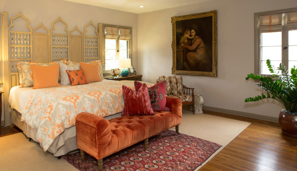 This is an example of a large mediterranean guest bedroom in Los Angeles with beige walls and medium hardwood floors.