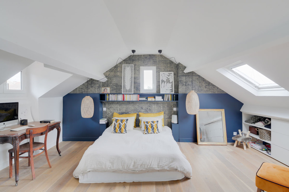 This is an example of a mid-sized contemporary loft-style bedroom in Paris with white walls and light hardwood floors.