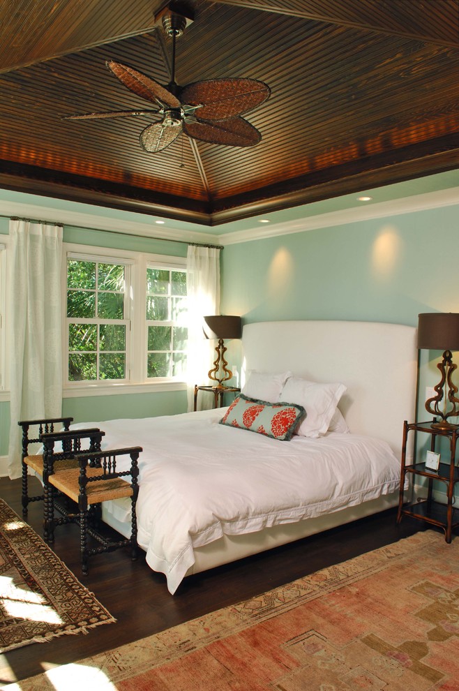 Large tropical master bedroom in Charleston with blue walls and dark hardwood floors.