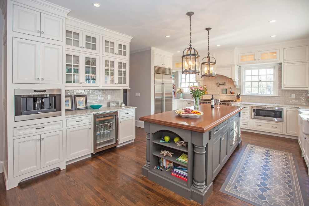 Inspiration for a mid-sized timeless u-shaped dark wood floor and brown floor eat-in kitchen remodel in Boston with a farmhouse sink, beaded inset cabinets, white cabinets, wood countertops, beige backsplash, cement tile backsplash, stainless steel appliances and an island