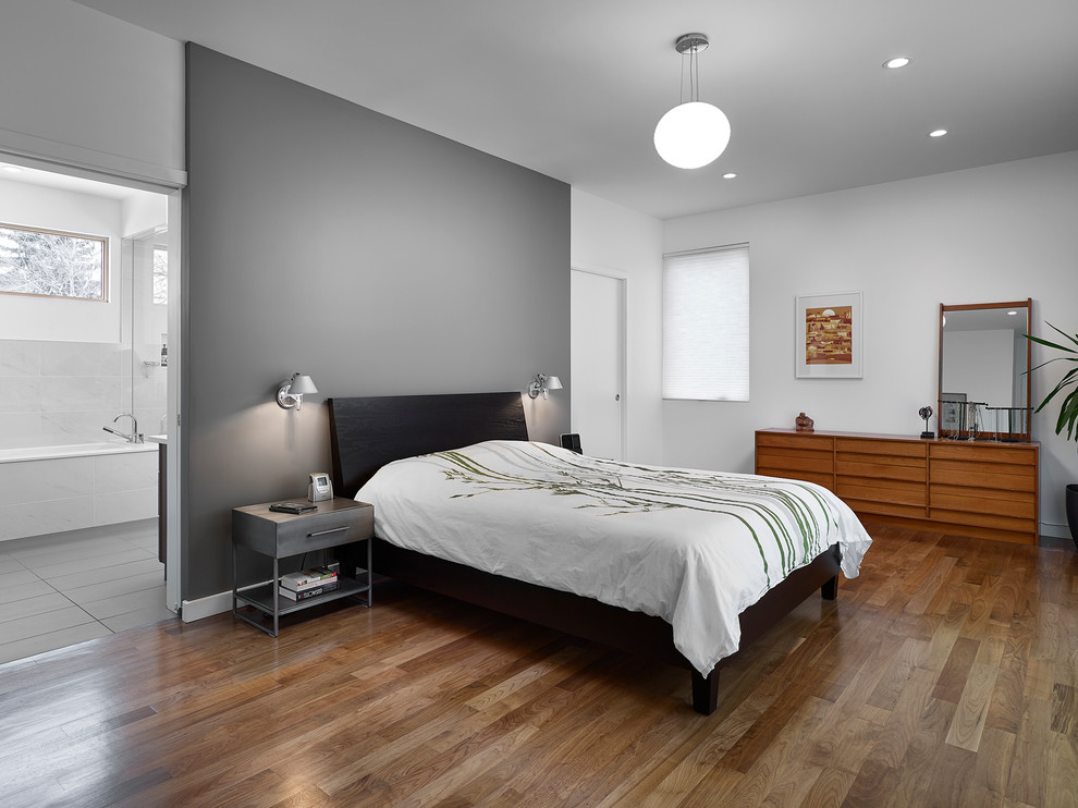 Inspiration for a large midcentury master bedroom in Edmonton with medium hardwood floors, multi-coloured walls, no fireplace and brown floor.