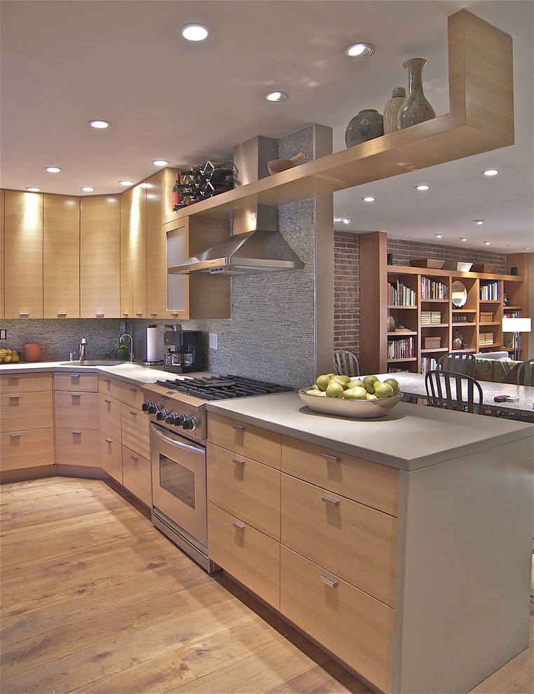 Design ideas for a mid-sized contemporary l-shaped eat-in kitchen in New York with concrete benchtops, stainless steel appliances, flat-panel cabinets, light wood cabinets, a drop-in sink and limestone splashback.