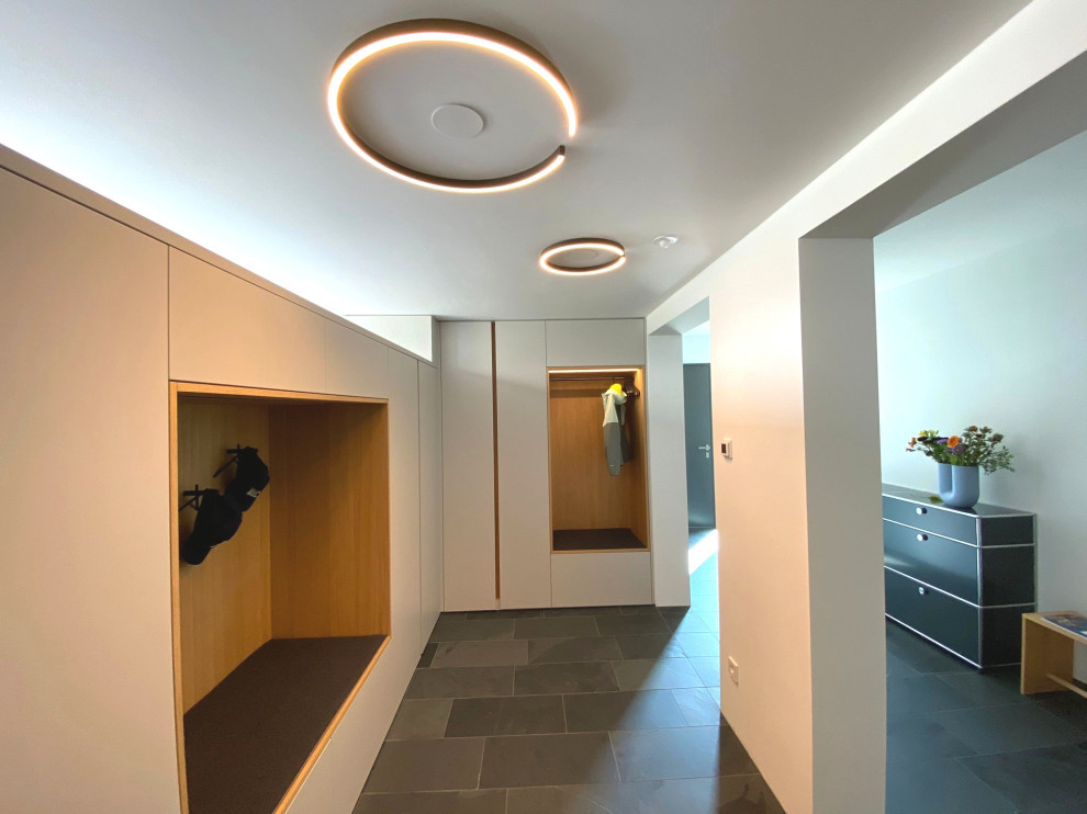 Idee per un ingresso o corridoio minimalista di medie dimensioni con pareti bianche, pavimento in ardesia e pavimento nero
