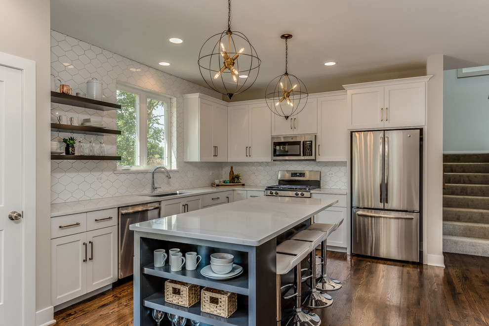 This is an example of a mid-sized modern l-shaped eat-in kitchen in Chicago with white cabinets, with island, white benchtop, a single-bowl sink, white splashback, stainless steel appliances, dark hardwood floors, brown floor and shaker cabinets.
