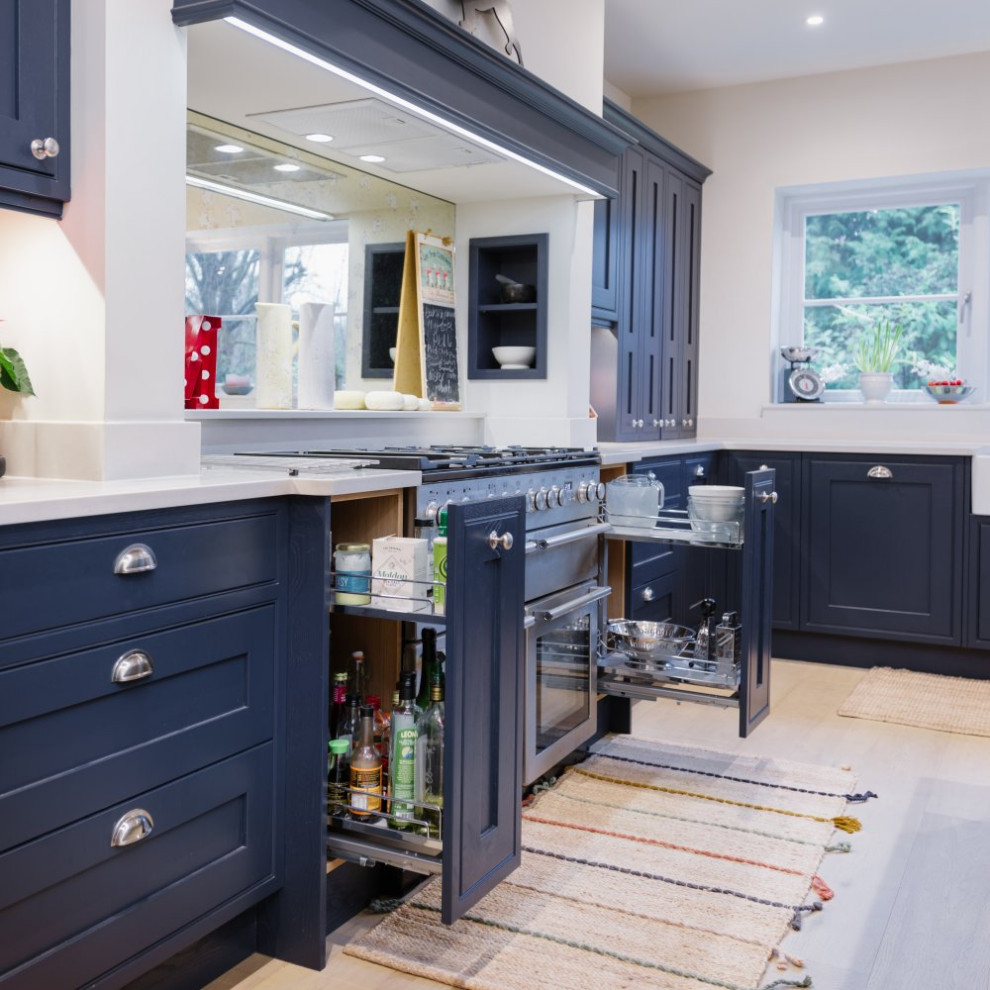 Design ideas for a mid-sized u-shaped eat-in kitchen in Sussex with shaker cabinets, blue cabinets, wood benchtops, multi-coloured splashback, mirror splashback, stainless steel appliances, light hardwood floors, with island, brown floor and brown benchtop.
