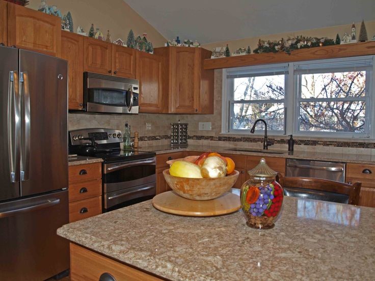 Eat-in kitchen - mid-sized transitional l-shaped eat-in kitchen idea with a drop-in sink, raised-panel cabinets, medium tone wood cabinets, quartz countertops, multicolored backsplash, mosaic tile backsplash, stainless steel appliances and an island
