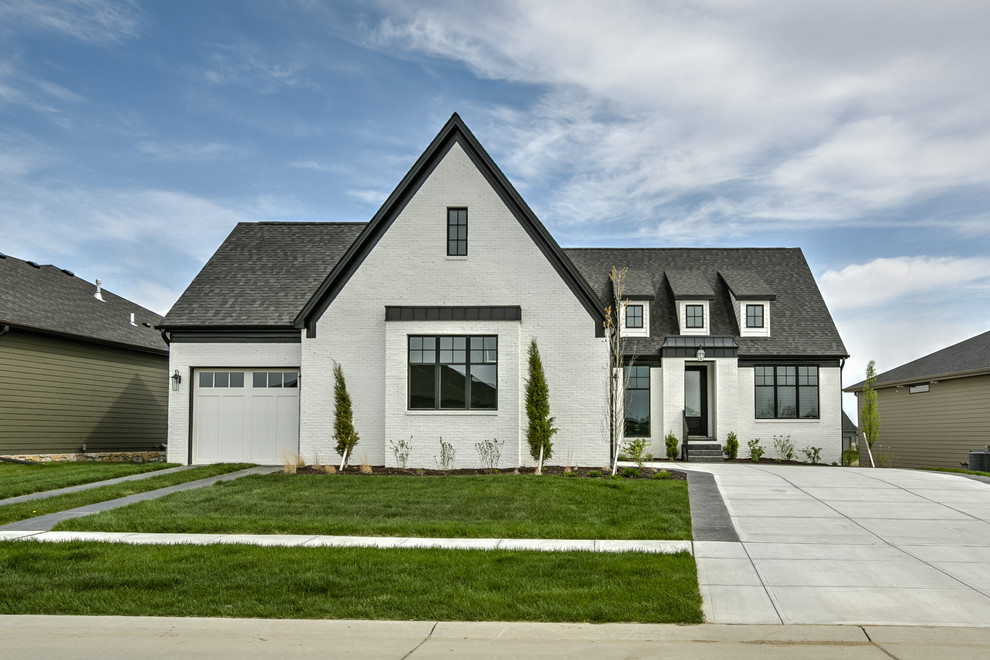 Cottage white one-story brick exterior home idea in Other with a shingle roof