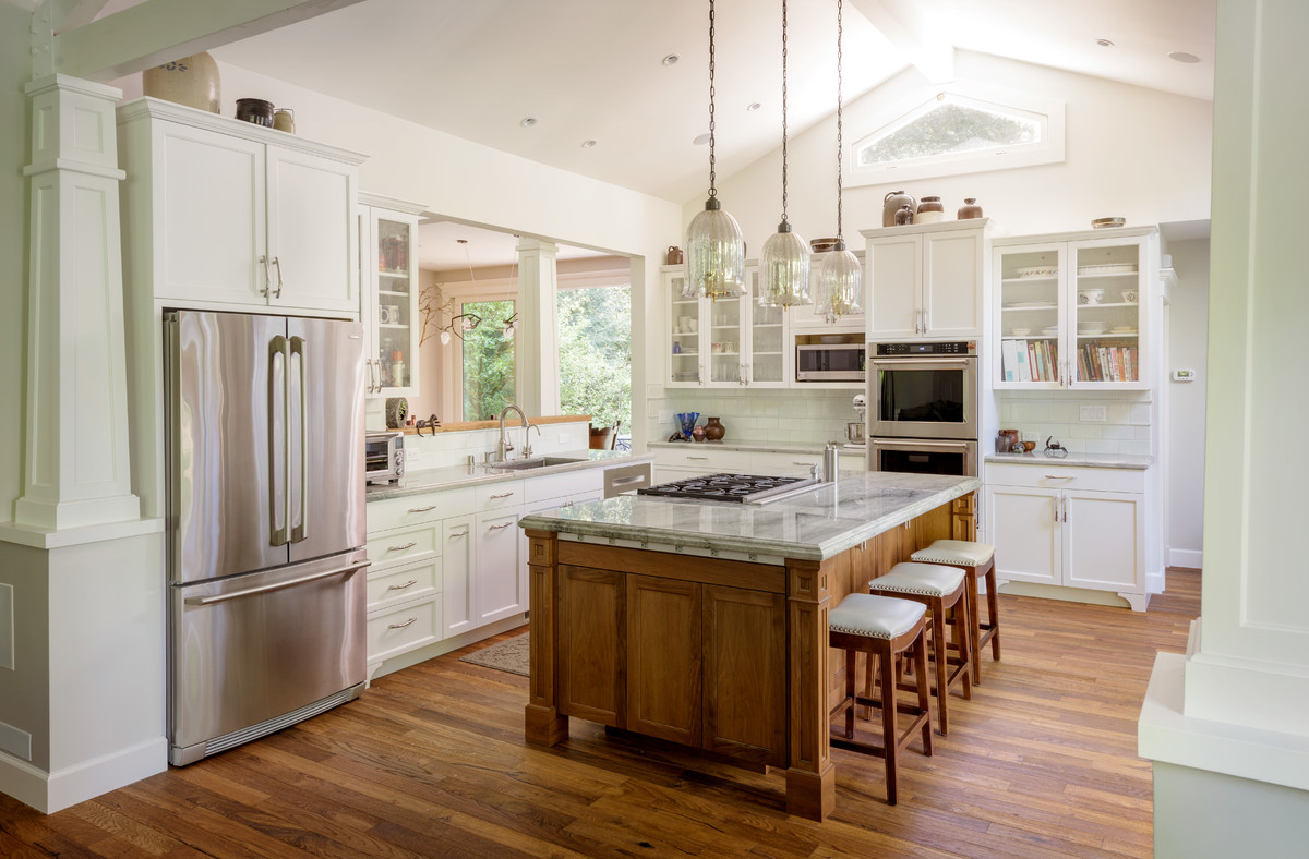 Design ideas for a traditional l-shaped open plan kitchen in San Francisco with an undermount sink, shaker cabinets, white cabinets, white splashback, stainless steel appliances, medium hardwood floors, with island and brown floor.