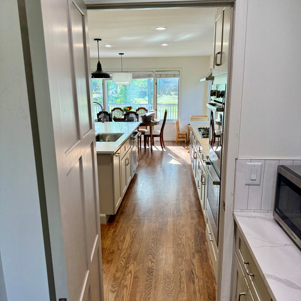 Eat-in kitchen - mid-sized transitional l-shaped medium tone wood floor, brown floor and wallpaper ceiling eat-in kitchen idea in Atlanta with an undermount sink, shaker cabinets, white cabinets, granite countertops, white backsplash, stainless steel appliances, an island and white countertops