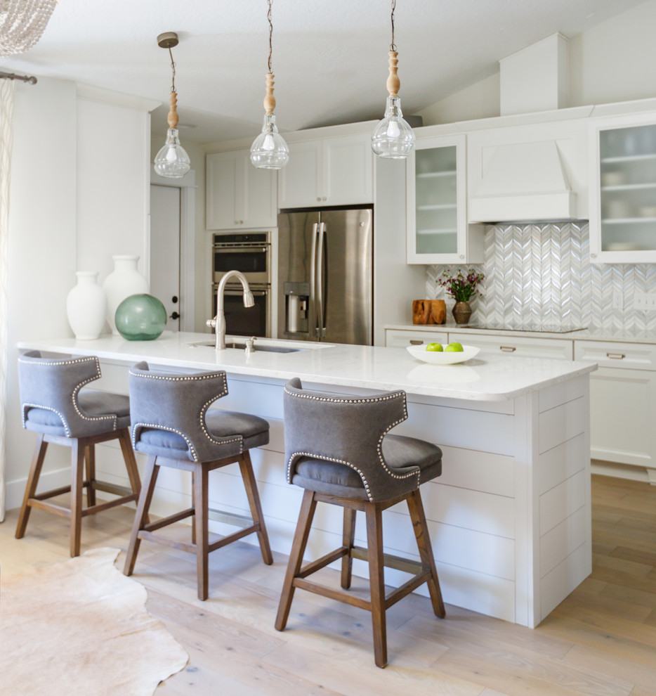 Open concept kitchen - contemporary galley light wood floor and beige floor open concept kitchen idea in Jacksonville with an undermount sink, shaker cabinets, white cabinets, multicolored backsplash, stainless steel appliances, a peninsula, white countertops, solid surface countertops and matchstick tile backsplash