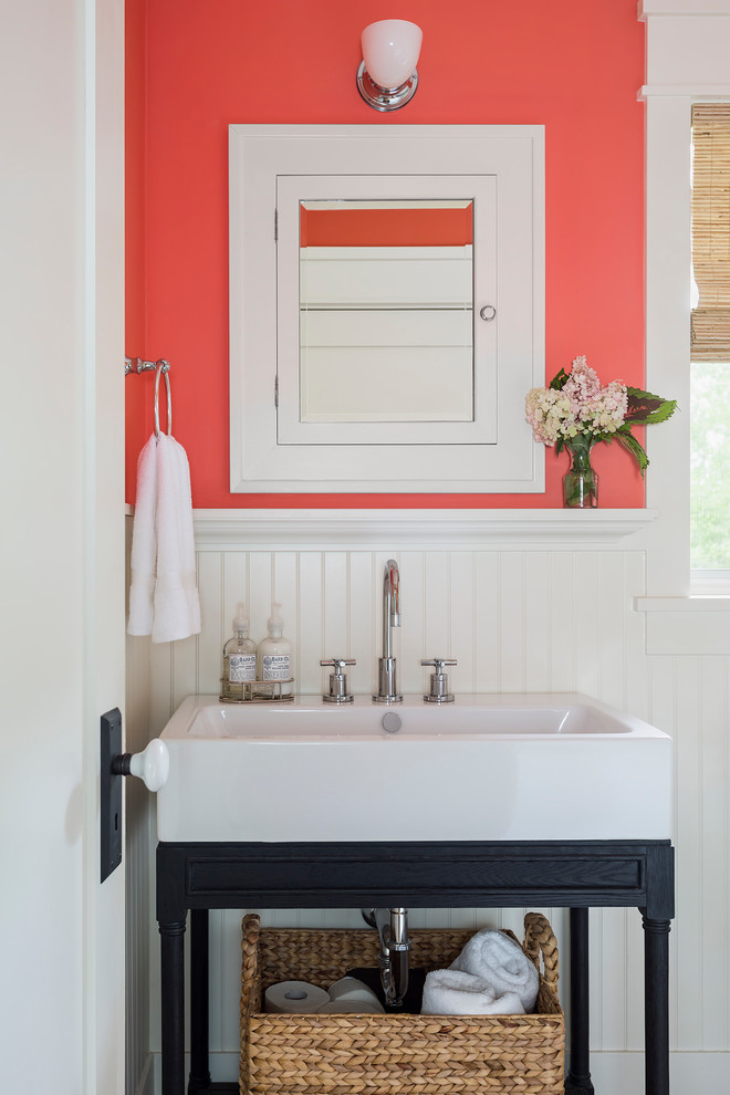 This is an example of a large traditional powder room in Los Angeles with furniture-like cabinets, pink walls, a console sink and black cabinets.