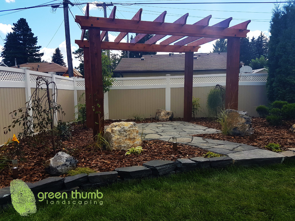 Inspiration for a rustic full sun backyard stone retaining wall landscape in Edmonton for summer.