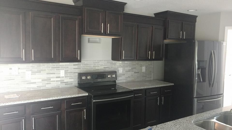 Inspiration for a mid-sized transitional galley open concept kitchen remodel in Orlando with a double-bowl sink, recessed-panel cabinets, dark wood cabinets, quartz countertops, gray backsplash, ceramic backsplash, stainless steel appliances and an island