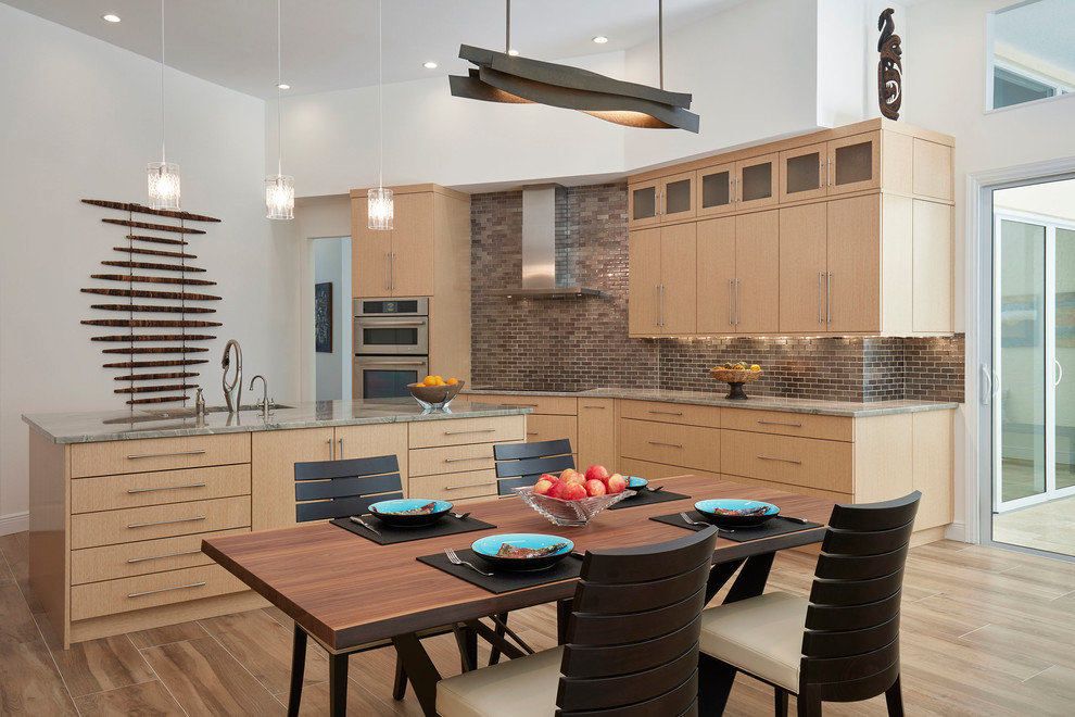 This is an example of a contemporary eat-in kitchen in Miami with flat-panel cabinets, light wood cabinets, metallic splashback, metal splashback, stainless steel appliances, with island and beige floor.