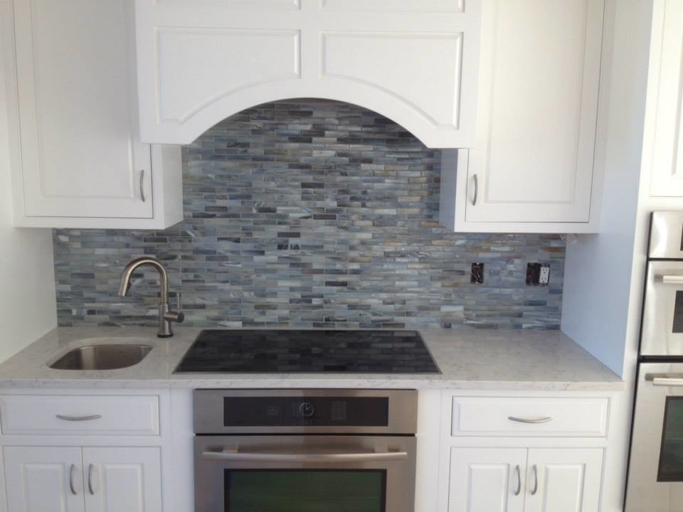 Inspiration for a transitional kitchen remodel in Boston with an undermount sink, raised-panel cabinets, white cabinets, marble countertops, blue backsplash, glass tile backsplash and stainless steel appliances