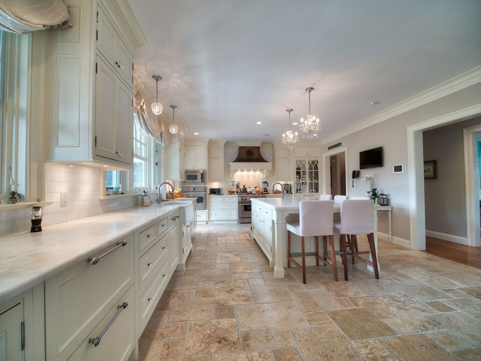 Photo of a large traditional l-shaped eat-in kitchen in Boston with a farmhouse sink, recessed-panel cabinets, beige cabinets, marble benchtops, white splashback, marble splashback, panelled appliances, travertine floors, with island, beige floor and white benchtop.