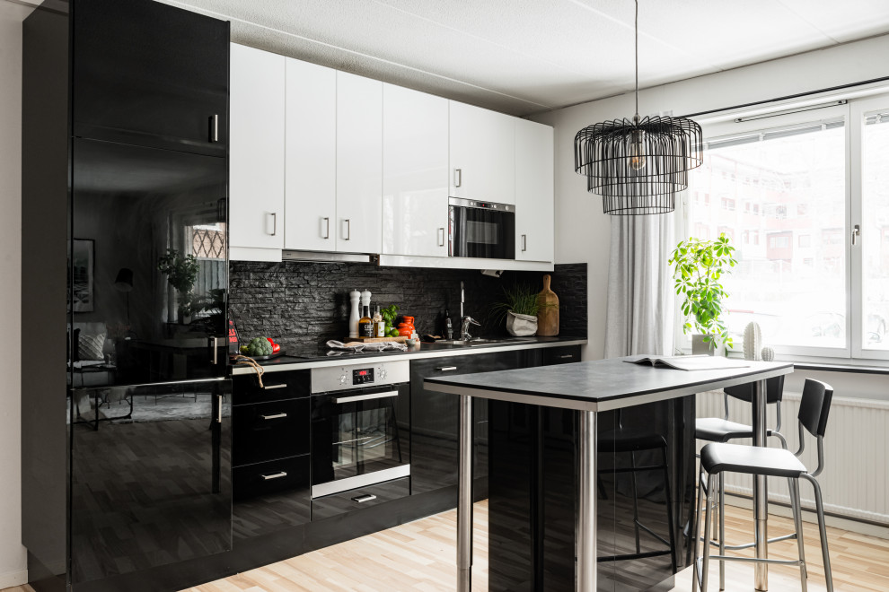 Idéer för skandinaviska svart kök, med släta luckor, svarta skåp, svart stänkskydd, ljust trägolv och en köksö