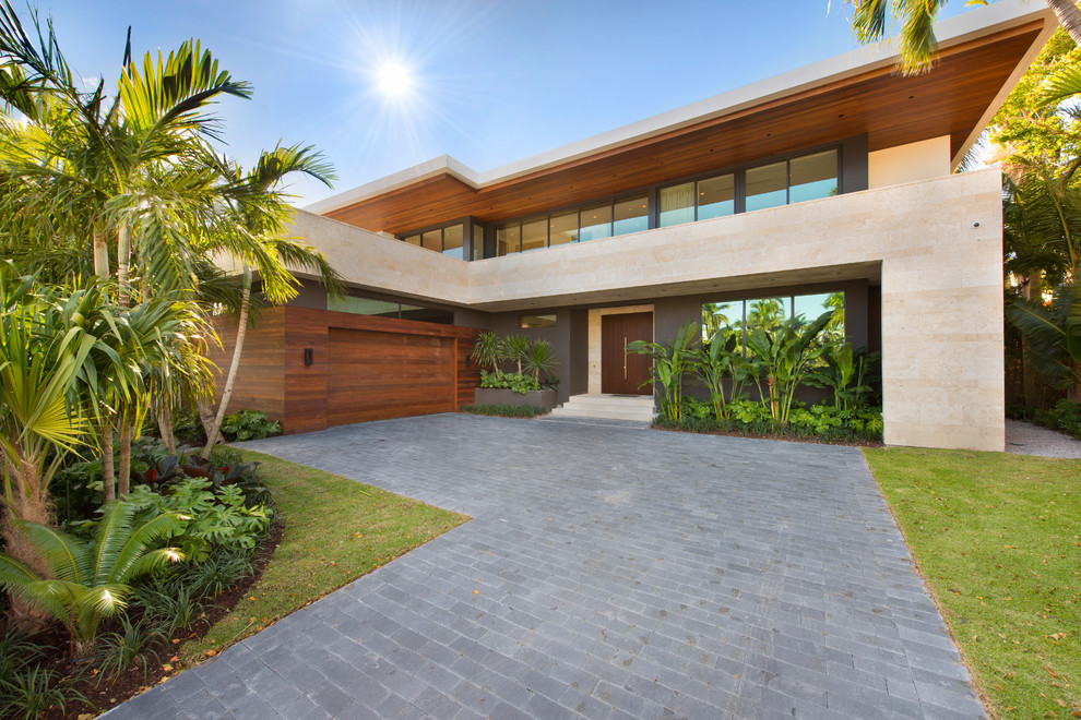 This is an example of a large modern two-storey brown house exterior in Miami with stone veneer and a flat roof.