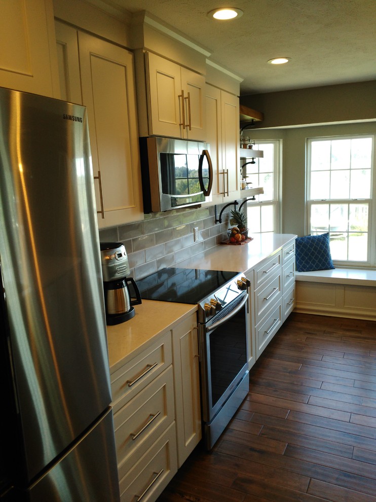 Inspiration for a mid-sized transitional l-shaped dark wood floor and brown floor eat-in kitchen remodel with a single-bowl sink, shaker cabinets, white cabinets, quartzite countertops, gray backsplash, ceramic backsplash, stainless steel appliances and an island