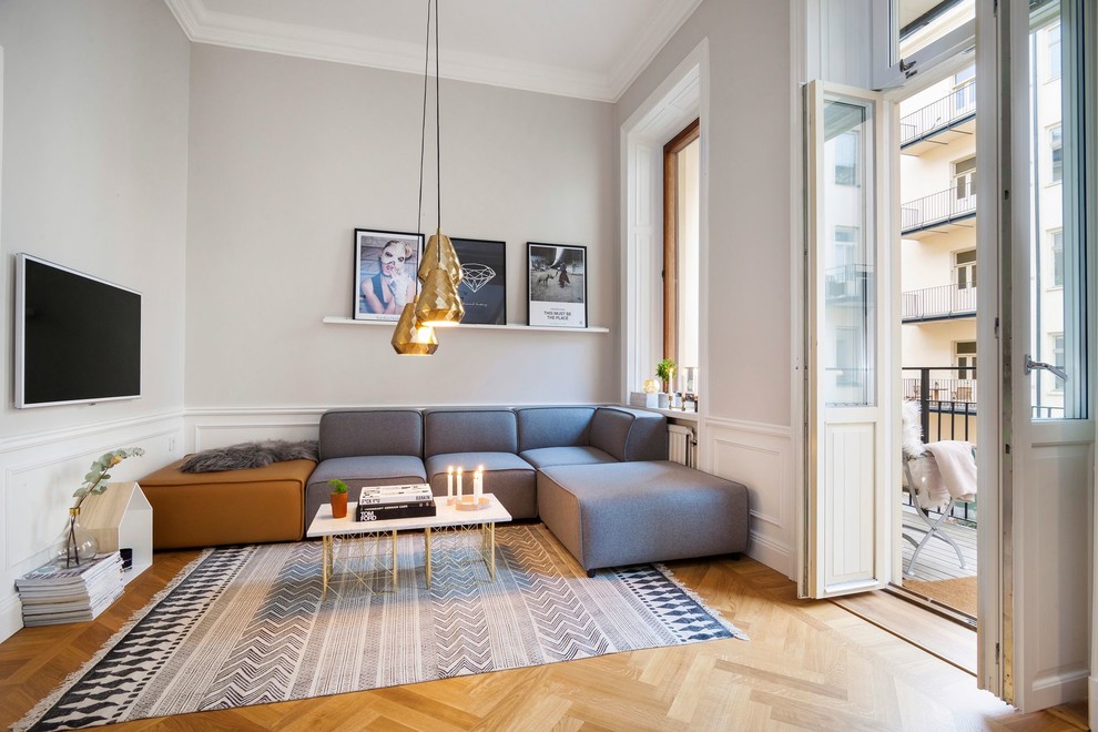This is an example of a large scandinavian formal open concept living room in Stockholm with grey walls, medium hardwood floors, no fireplace and a wall-mounted tv.