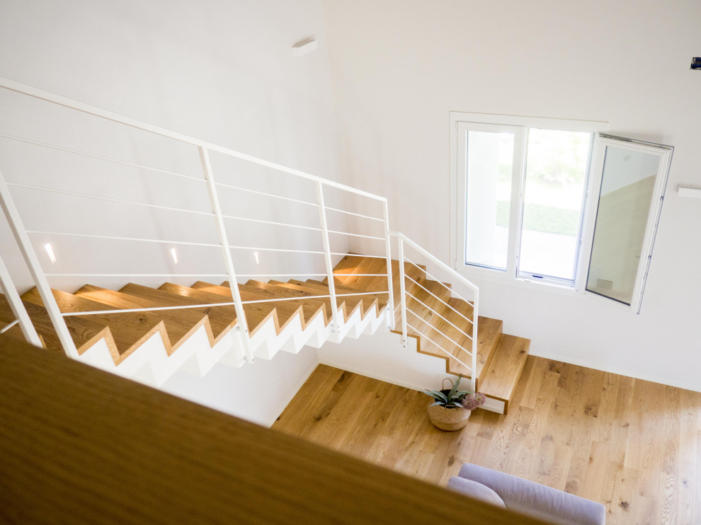 На фото: большая прямая деревянная лестница в скандинавском стиле с деревянными ступенями и металлическими перилами