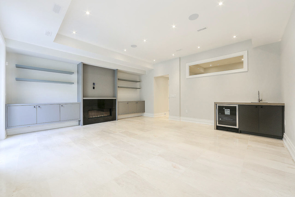Photo of a large transitional walk-out basement in Toronto with white walls, marble floors, a standard fireplace, a stone fireplace surround and beige floor.