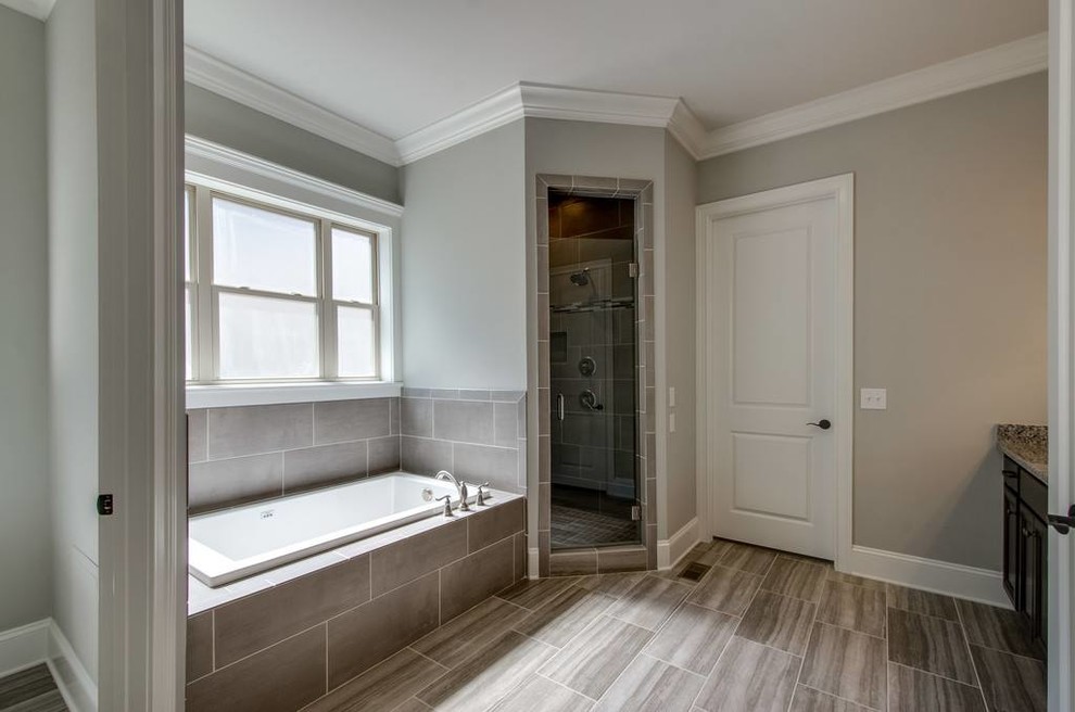 Mid-sized transitional 3/4 gray tile and porcelain tile porcelain tile and gray floor corner shower photo with recessed-panel cabinets, black cabinets, beige walls, an undermount sink, granite countertops and a hinged shower door