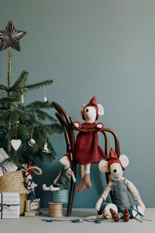 Fabric toy mice sitting at a miniature table with tea and Christmas treats styled under a tree.