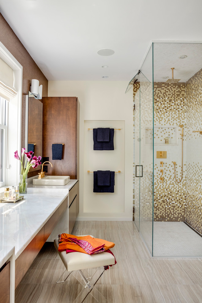 This is an example of a large contemporary master bathroom in Boston with flat-panel cabinets, a corner shower, multi-coloured tile, marble benchtops, a hinged shower door, mosaic tile, beige walls, a vessel sink, beige floor, white benchtops and brown cabinets.