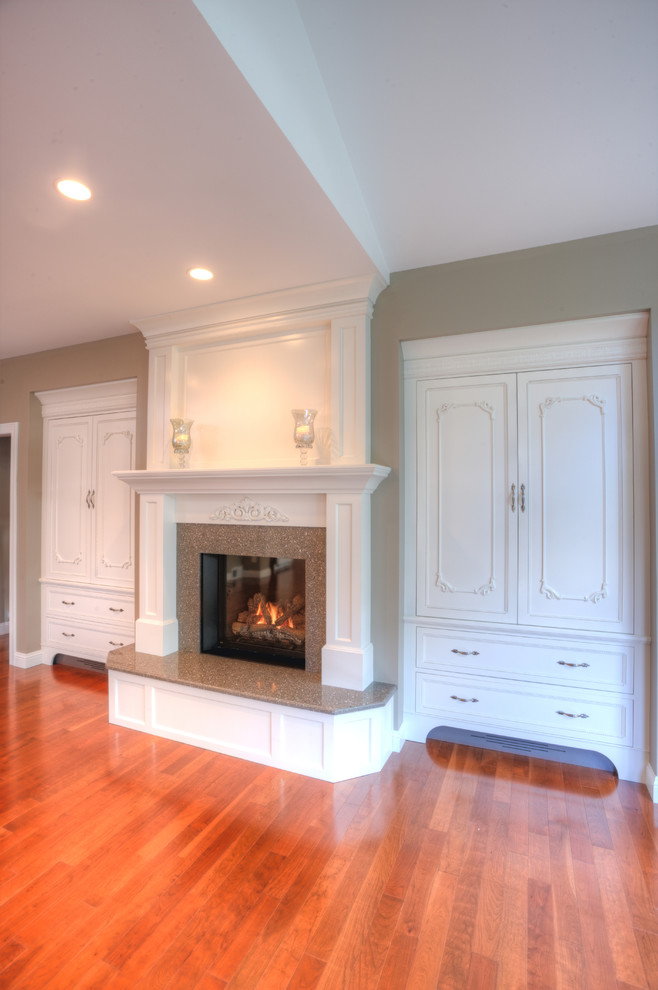 This is an example of a mid-sized traditional formal open concept living room in Milwaukee with beige walls, light hardwood floors, a standard fireplace and a concealed tv.