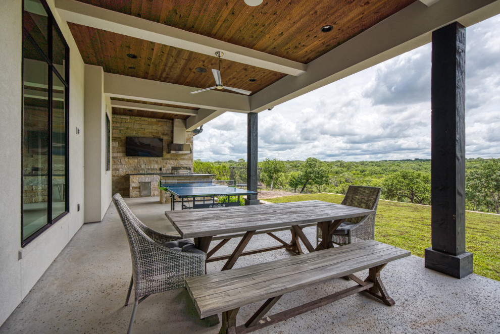 Exemple d'une terrasse arrière chic avec une cuisine d'été et une extension de toiture.