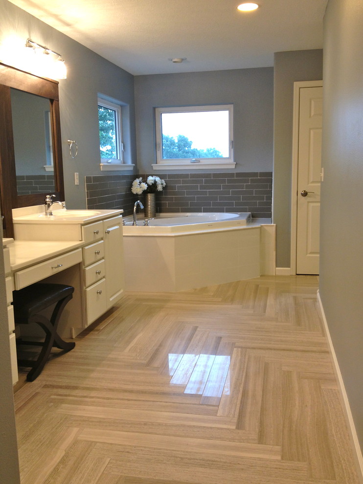 Inspiration for a large transitional master gray tile and ceramic tile ceramic tile corner bathtub remodel in Cedar Rapids with an integrated sink, raised-panel cabinets, white cabinets and gray walls