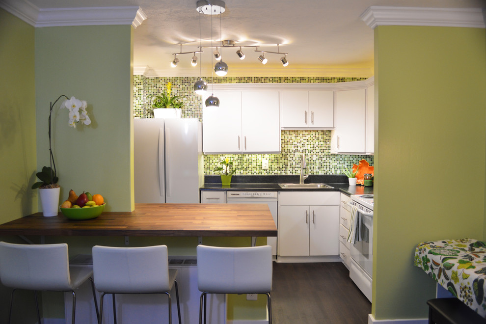 This is an example of a small asian l-shaped open plan kitchen in Salt Lake City with a drop-in sink, flat-panel cabinets, white cabinets, laminate benchtops, green splashback, glass tile splashback, white appliances, vinyl floors and with island.