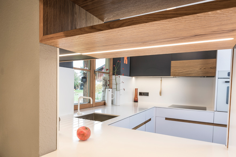 Geschlossene, Kleine Nordische Küche in U-Form mit Unterbauwaschbecken, flächenbündigen Schrankfronten, weißen Schränken, Mineralwerkstoff-Arbeitsplatte, Küchenrückwand in Weiß, weißen Elektrogeräten und Linoleum in München