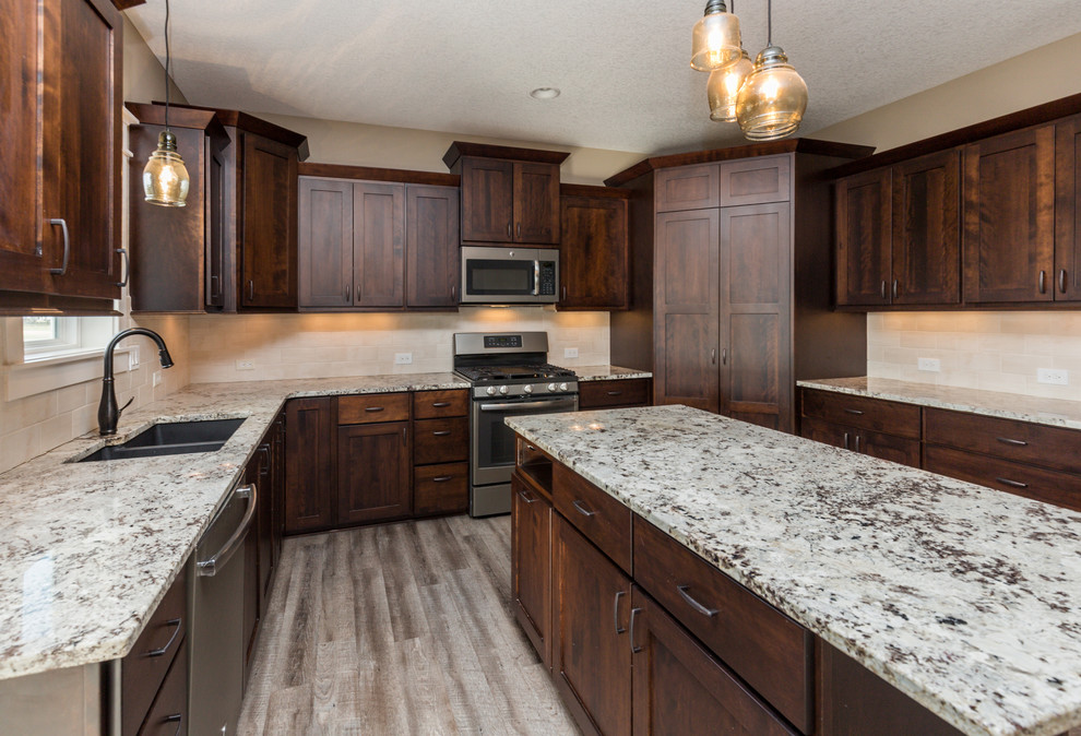 Transitional u-shaped vinyl floor and gray floor eat-in kitchen photo with an undermount sink, shaker cabinets, dark wood cabinets, granite countertops, beige backsplash, ceramic backsplash, stainless steel appliances, an island and beige countertops