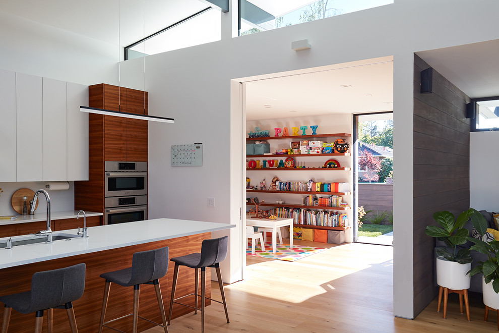 Los Altos New Residence - Klopf Architecture and Outer space Landscape Architects designed a new warm, modern, open, indoor-outdoor home in Los Altos, California. Inspired by mid-century modern homes but looking for something completely new and custom, the owners, a couple with two children, bought an older ranch style home with the intention of replacing it. 

Created on a grid, the house is designed to be at rest with differentiated spaces for activities; living, playing, cooking, dining and a piano space. The low-sloping gable roof over the great room brings a grand feeling to the space. The clerestory windows at the high sloping roof make the grand space light and airy. 
Upon entering the house, an open atrium entry in the middle of the house provides light and nature to the great room. The Heath tile wall at the back of the atrium blocks direct view of the rear yard from the entry door for privacy. 
The bedrooms, bathrooms, play room and the sitting room are under flat wing-like roofs that balance on either side of the low sloping gable roof of the main space. Large sliding glass panels and pocketing glass doors foster openness to the front and back yards. In the front there is a fenced-in play space connected to the play room, creating an indoor-outdoor play space that could change in use over the years. The play room can also be closed off from the great room with a large pocketing door. In the rear, everything opens up to a deck overlooking a pool where the family can come together outdoors.
Wood siding travels from exterior to interior, accentuating the indoor-outdoor nature of the house. Where the exterior siding doesn’t come inside, a palette of white oak floors, white walls, walnut cabinetry, and dark window frames ties all the spaces together to create a uniform feeling and flow throughout the house. The custom cabinetry matches the minimal joinery of the rest of the house, a trim-less, minimal appearance. Wood siding was mitered in the corners, including where siding meets the interior drywall. Wall materials were held up off the floor with a minimal reveal. This tight detailing gives a sense of cleanliness to the house. 
The garage door of the house is completely flush and of the same material as the garage wall, de-emphasizing the garage door and making the street presentation of the house kinder to the neighborhood.
The house is akin to a custom, modern-day Eichler home in many ways. Inspired by mid-century modern homes with today’s materials, approaches, standards, and technologies. The goals were to create an indoor-outdoor home that was energy-efficient, light and flexible for young children to grow. This 3,000 square foot, 3 bedroom, 2.5 bathroom new house is located in Los Altos in the heart of the Silicon Valley. 


Klopf Architecture Project Team: John Klopf, AIA, and Chuang-Ming Liu
 Landscape Architect: Outer space Landscape Architects
 Structural Engineer: ZFA Structural Engineers
 Staging: Da Lusso Design 
 Photography ©2018 Mariko Reed
 Location: Los Altos, CA 
Year completed: 2017