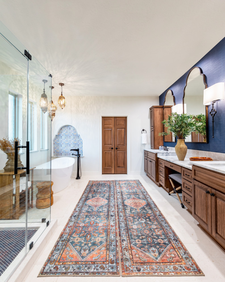 This is an example of a mediterranean master bathroom in Houston with raised-panel cabinets, medium wood cabinets, a freestanding tub, an alcove shower, white walls, an undermount sink, marble benchtops, white floor, a hinged shower door, multi-coloured benchtops, a double vanity and a built-in vanity.