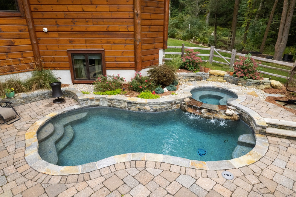 Immagine di una grande piscina chic personalizzata dietro casa con una vasca idromassaggio e pavimentazioni in cemento