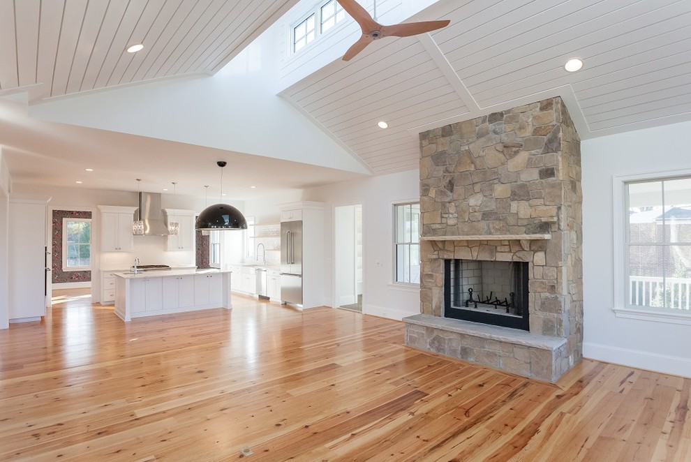 This is an example of a country open concept family room in DC Metro with white walls, light hardwood floors, a standard fireplace and a stone fireplace surround.