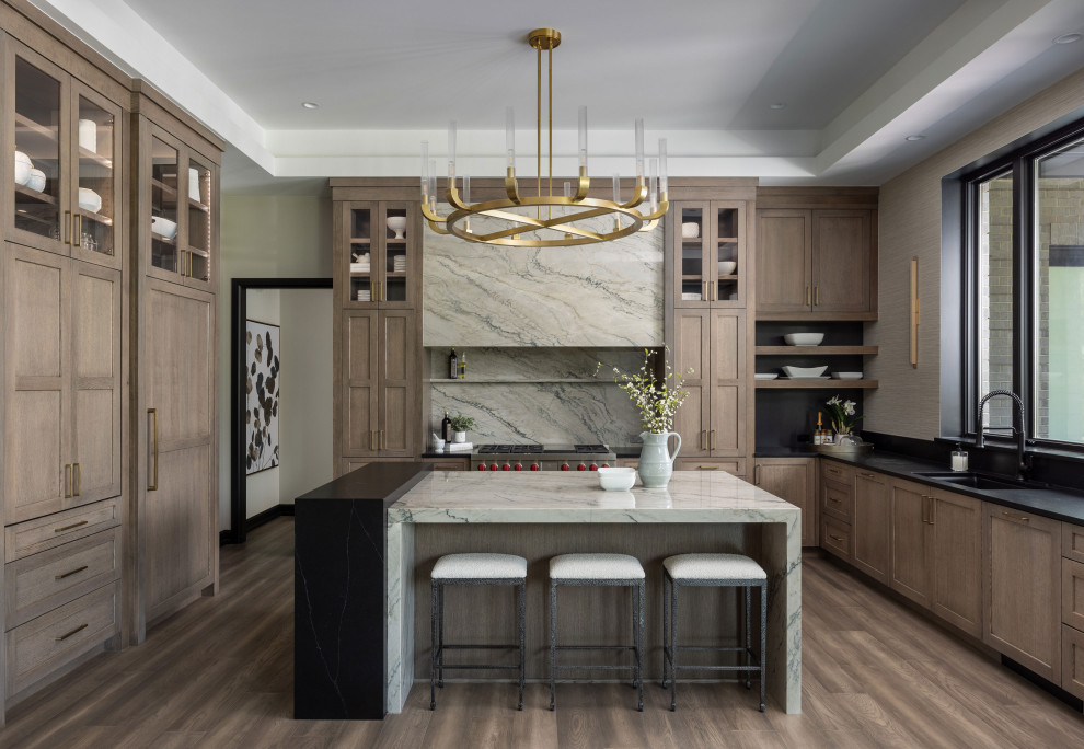 Photo of a transitional eat-in kitchen in Detroit with an undermount sink, shaker cabinets, medium wood cabinets, quartzite benchtops, grey splashback, engineered quartz splashback, panelled appliances, with island, brown floor, grey benchtop and recessed.