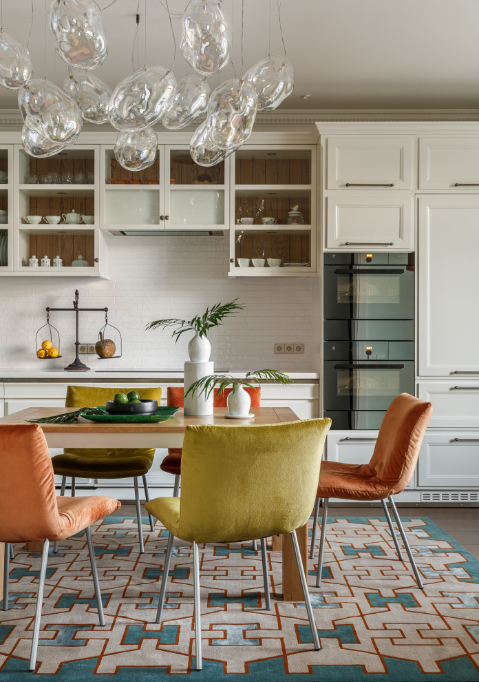This is an example of a mid-sized transitional single-wall eat-in kitchen in Moscow with recessed-panel cabinets, white cabinets, white splashback, cement tile splashback, panelled appliances, no island, multi-coloured floor and white benchtop.