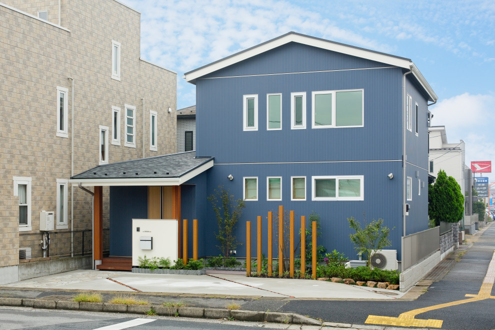 На фото: большой, двухэтажный, синий частный загородный дом в восточном стиле с комбинированной облицовкой, двускатной крышей, крышей из смешанных материалов, черной крышей и отделкой доской с нащельником